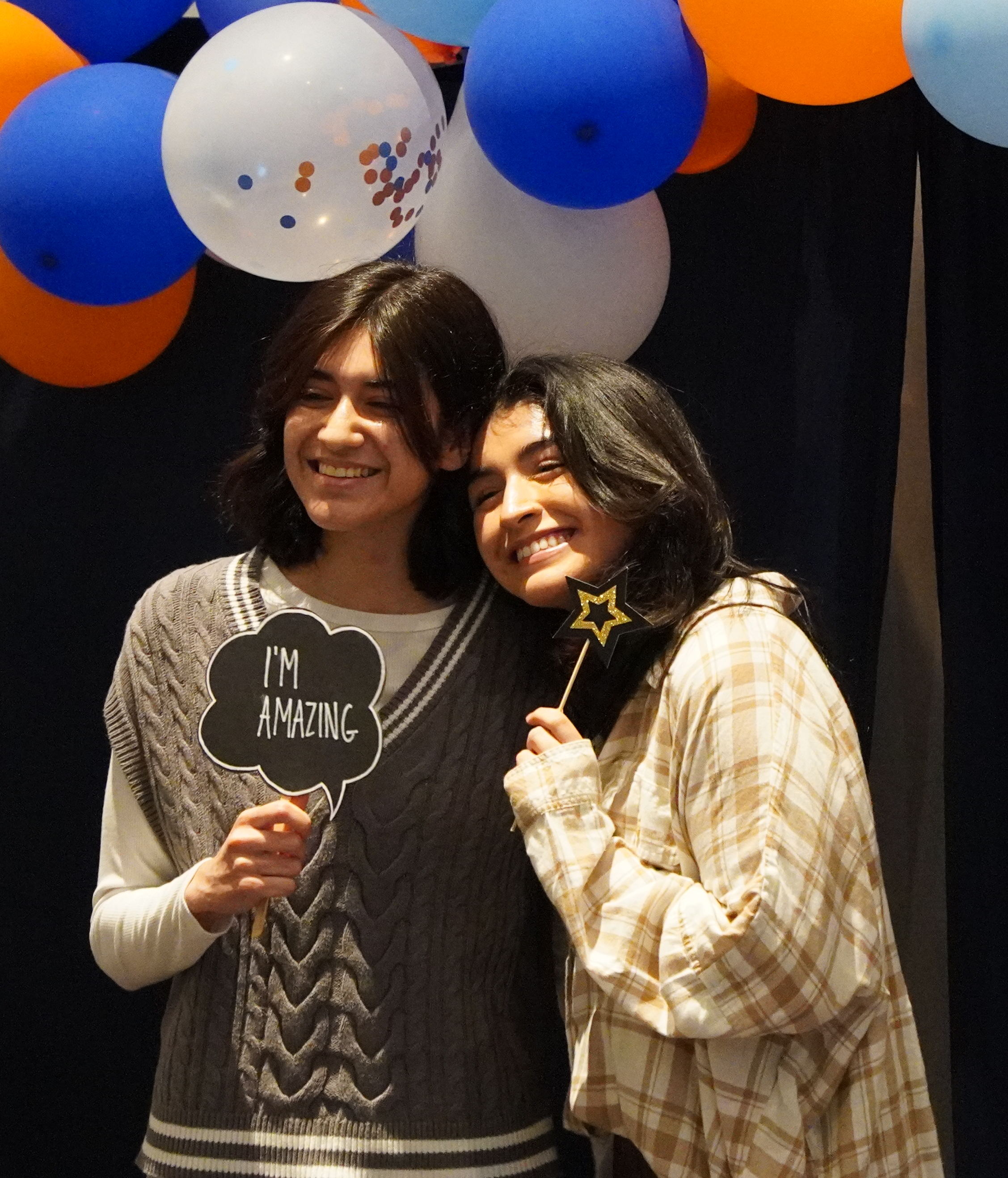 Two students posing in front of balloon arc and smiling