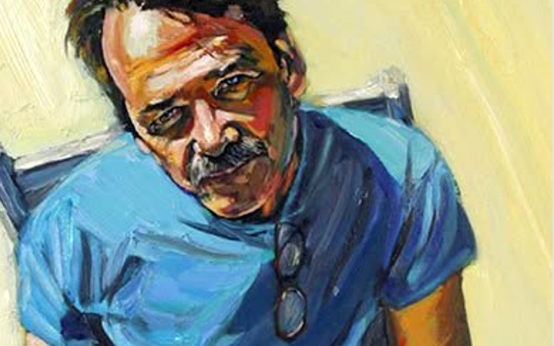 A man with a moustache wearing a blue shirt.