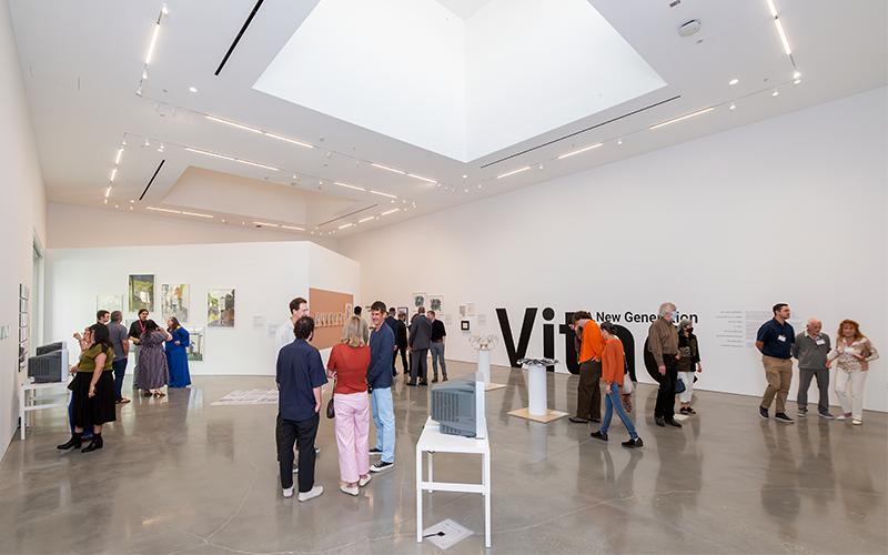 Gallery with people talking and viewing art.