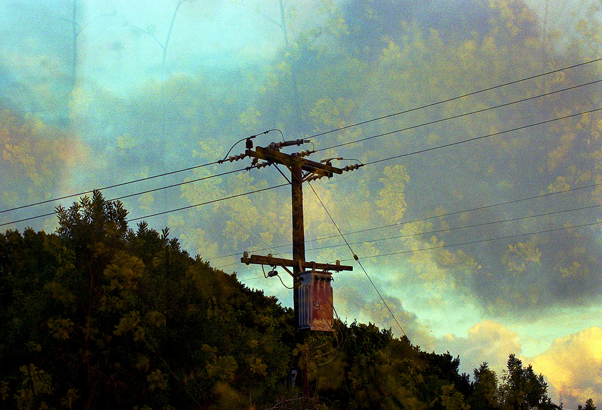 Telephone pole on a hillside against a colorful sky.