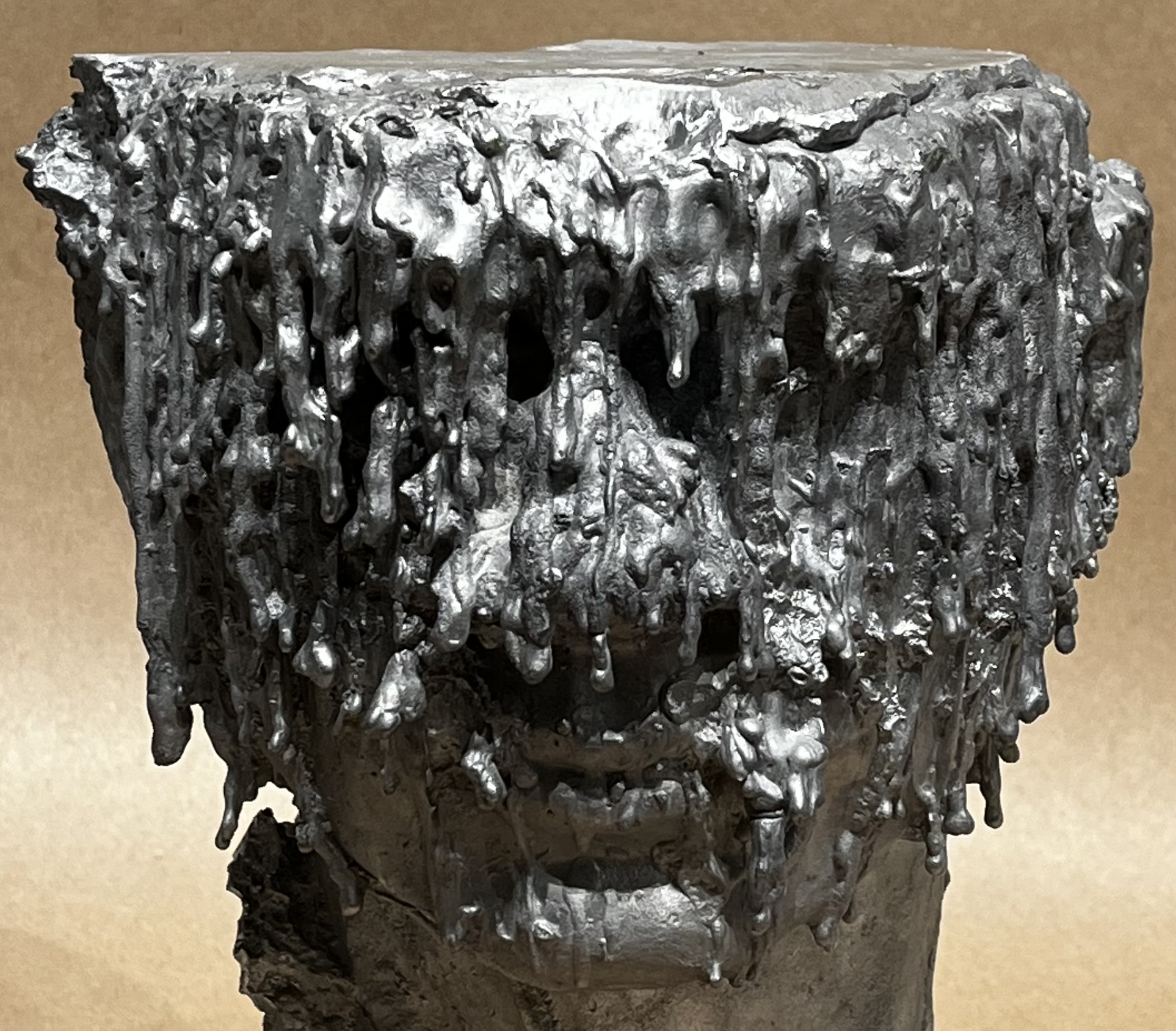Head form with dripping sculptural elements.