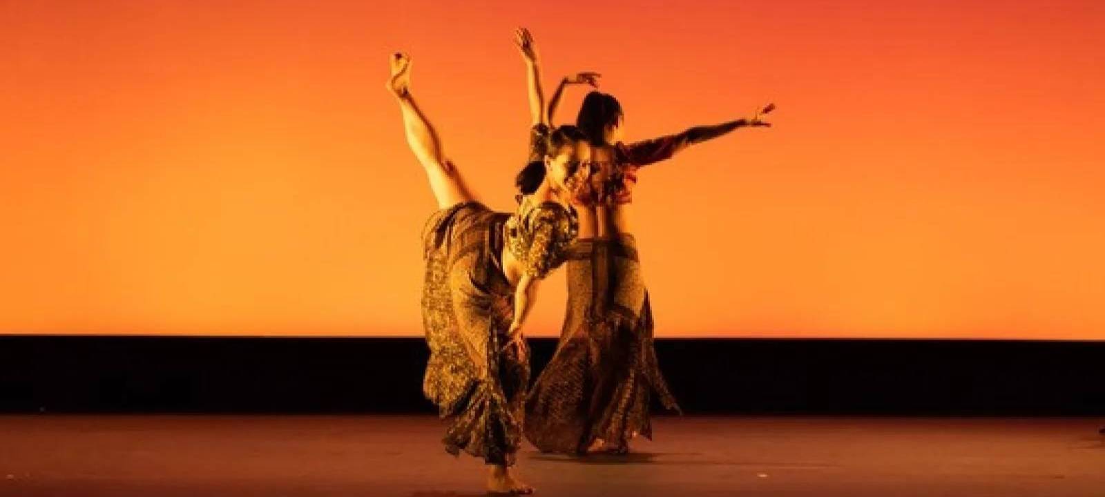 Students dancing on stage under orange spotlight