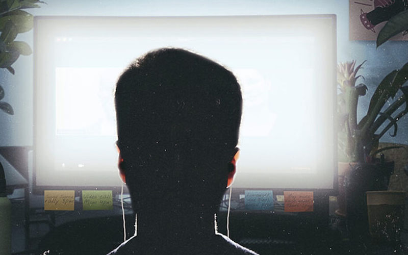 Silhouette of figure in front of computer screen