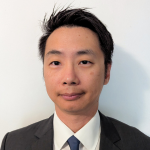 man in black suit and tie poses for picture