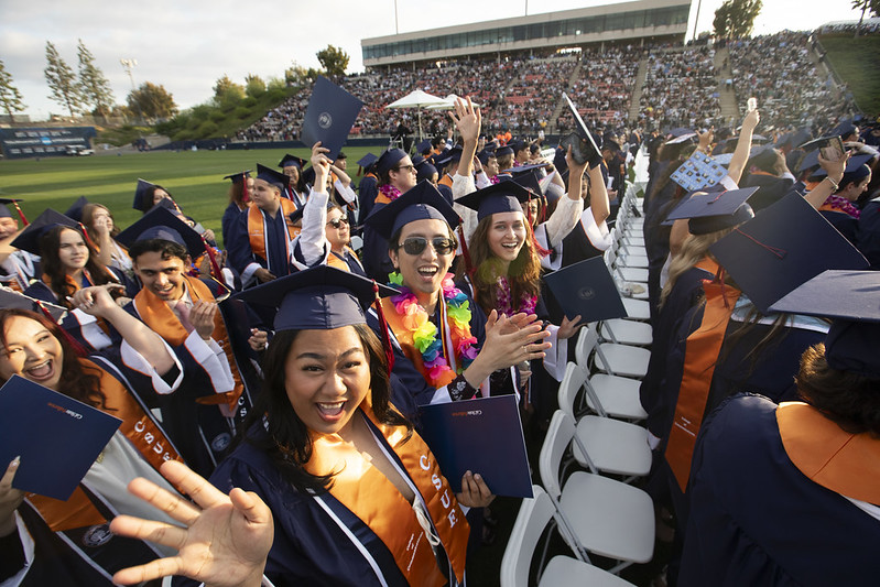 CSUF class of 2024 students cheering while on the stadium field during commencement