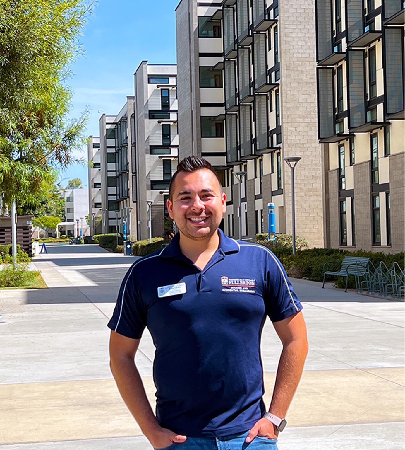 Person standing in navy blue housing and residentail engagement polo and white nametag