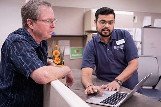 ATC staff assisting a faculty member with adding software on their laptop