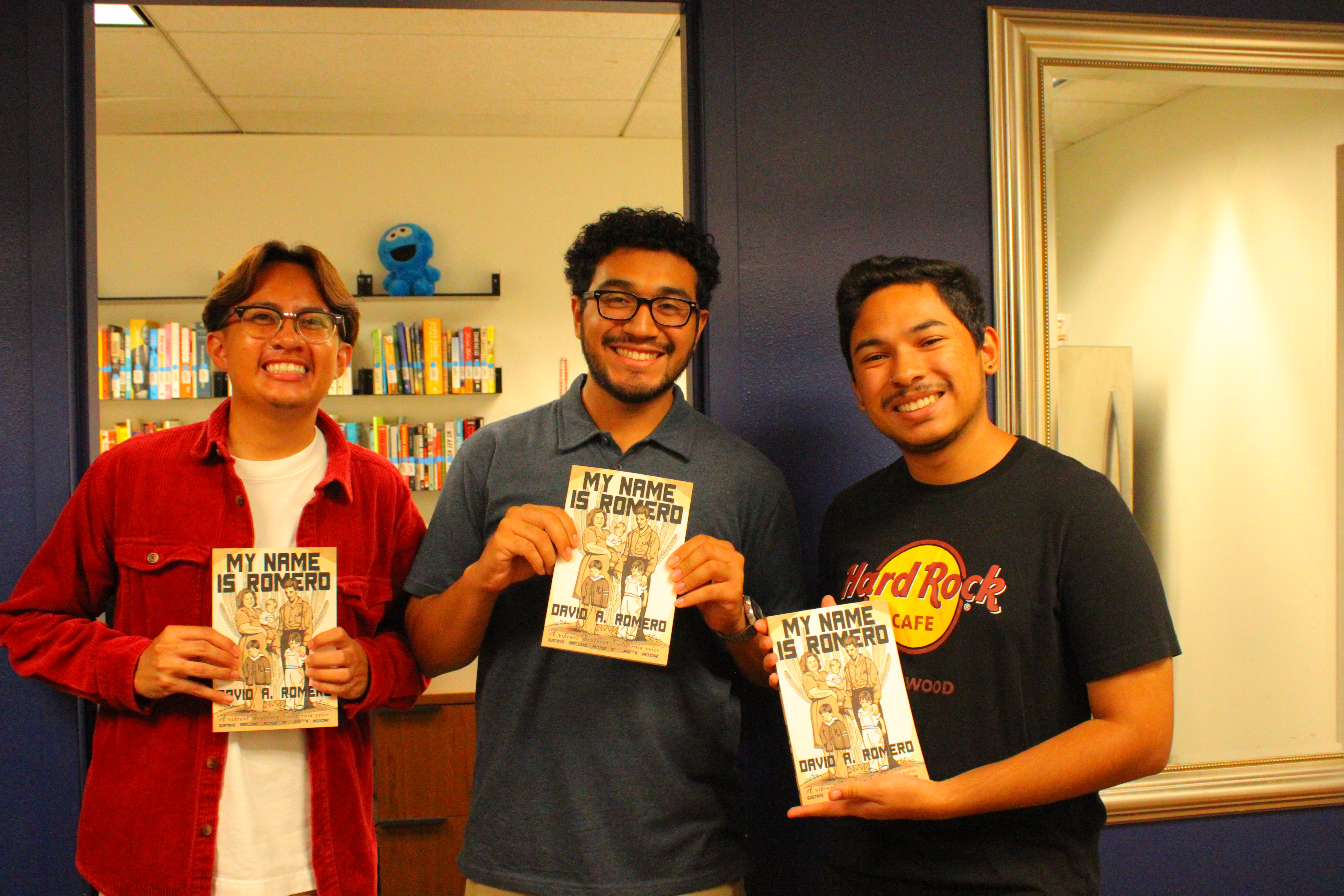3 MSI students holding books and posing for camera in front of center