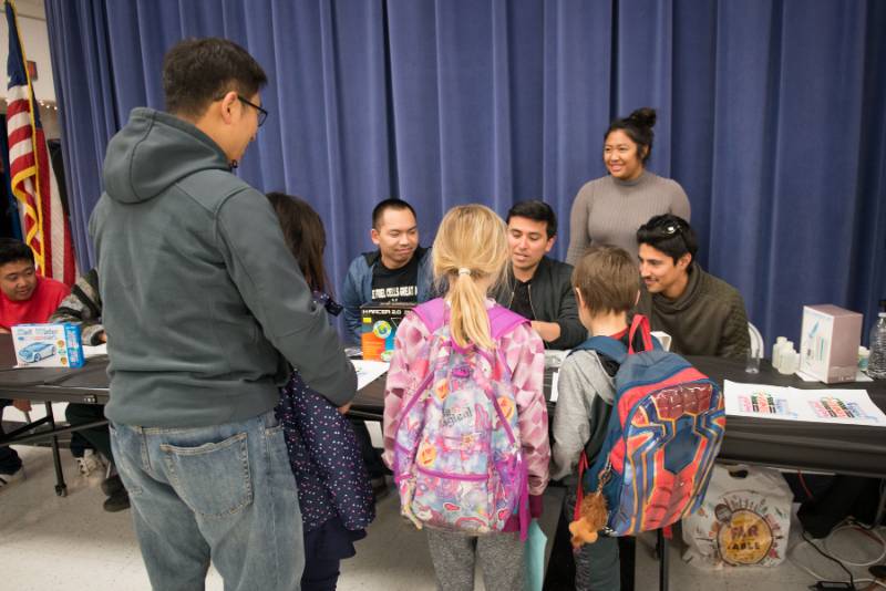 Elementary school students talking to CSUF students.