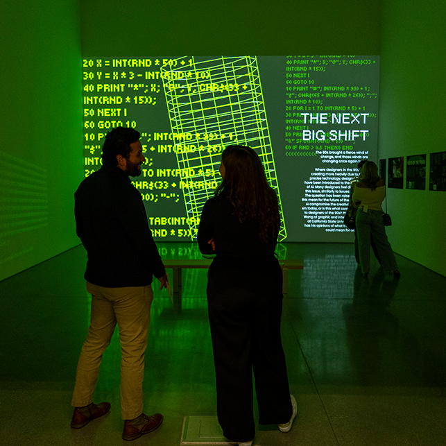 Two people in a gallery looking at a digital projection.