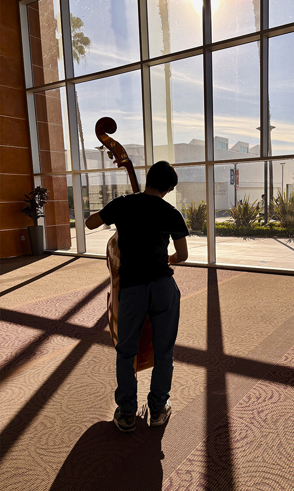 Bass player rehearsing in a building lobby.