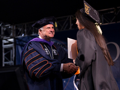 President Virgee and student at graduation ceremony.