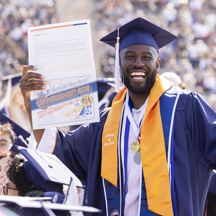Man in graduation regalia holding a diploma.