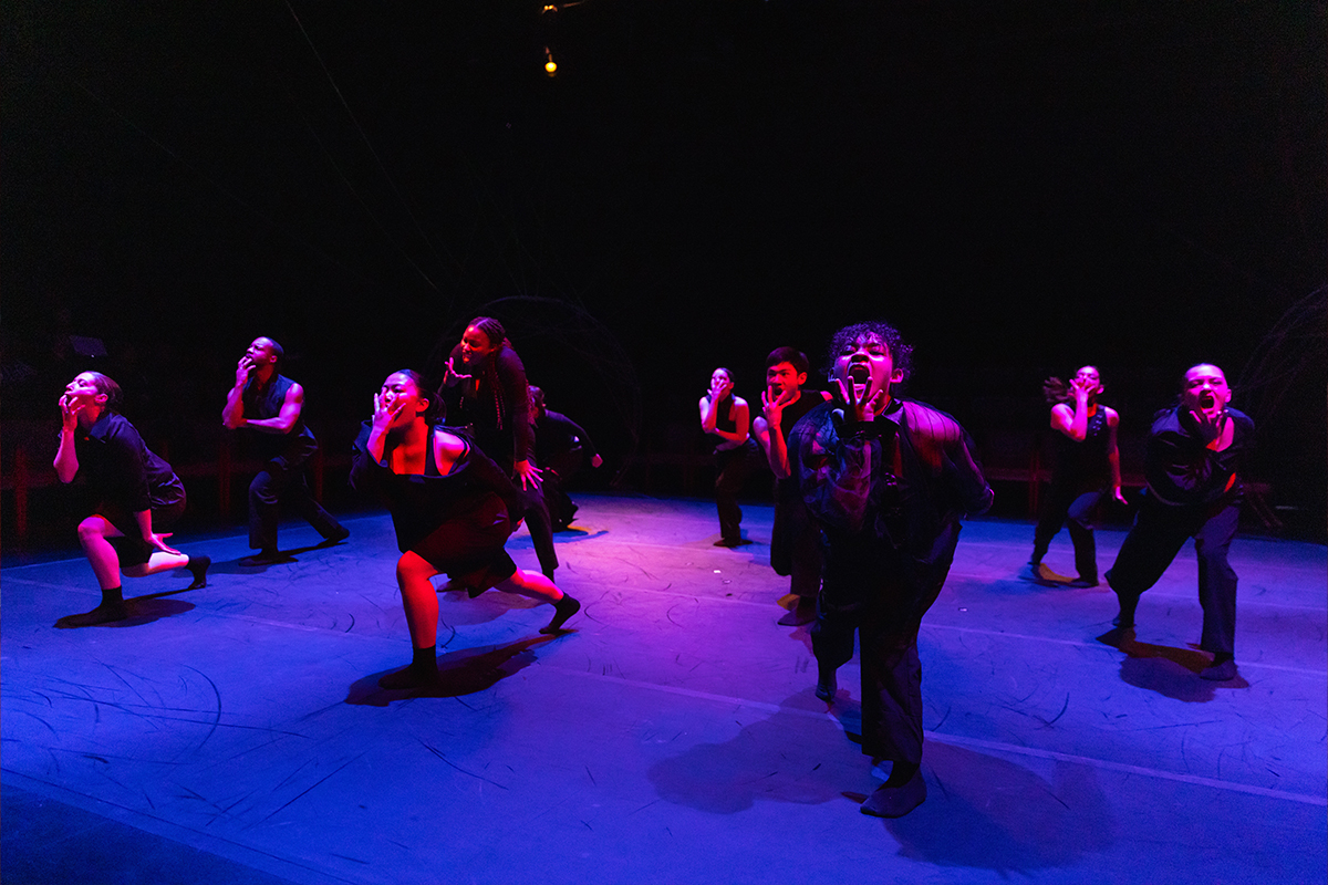 Dancers performing under blue and magenta lighting.