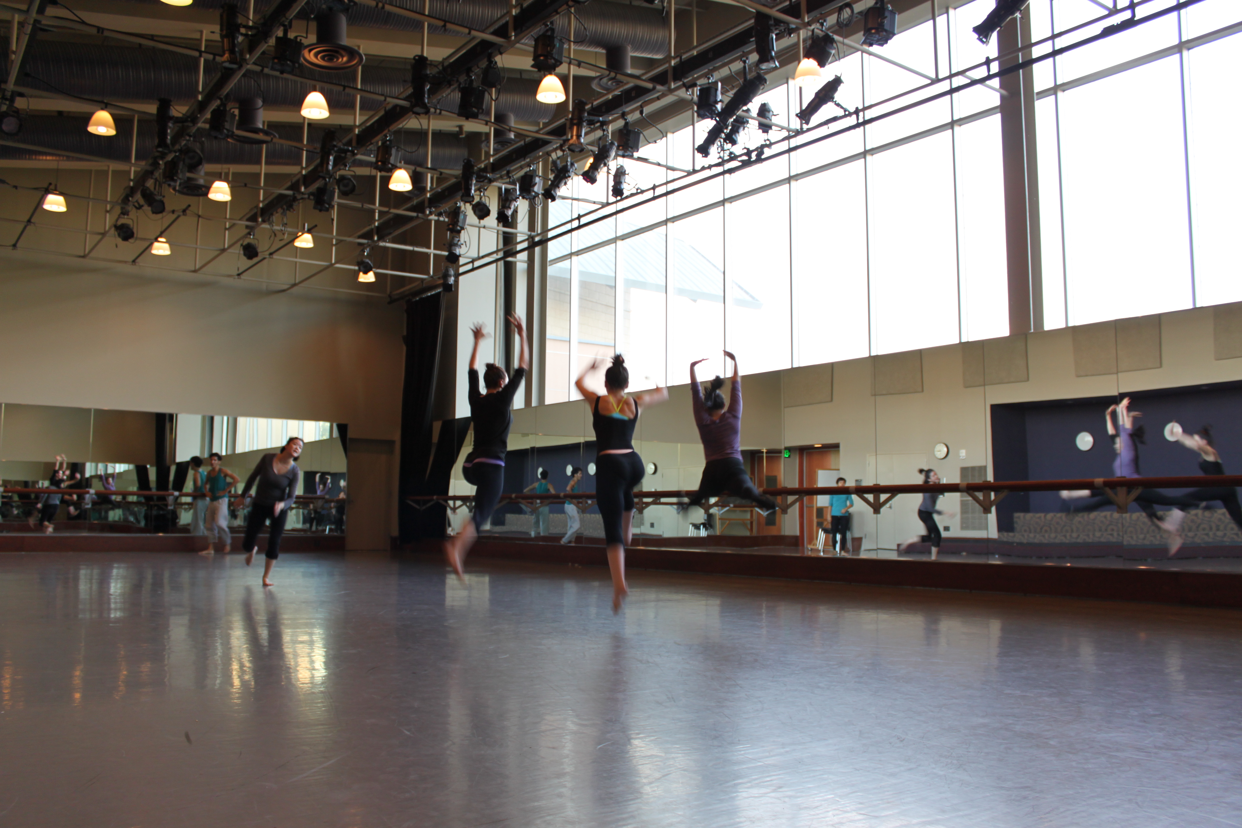 Dancers leaping in a dance studio.