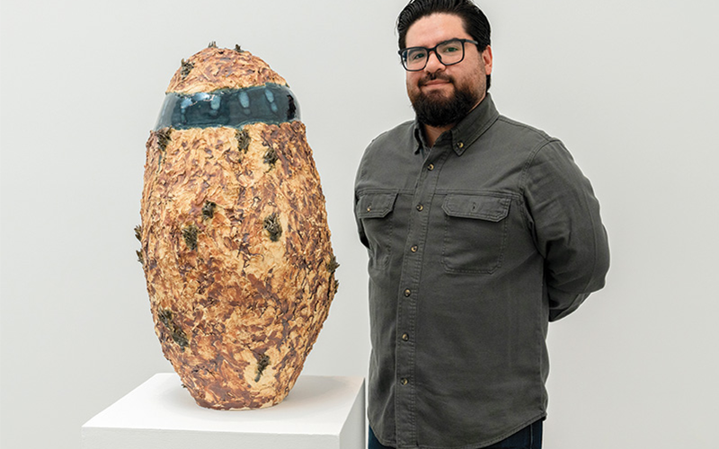 Man standing next to a cermic vessel.