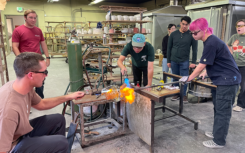 Men and women shaping molten glass.
