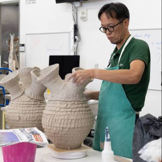 Man working on a clay form.