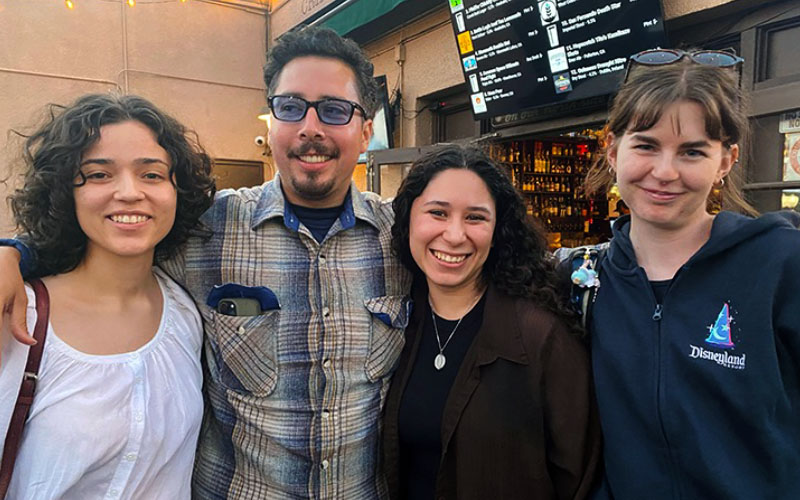 Four people with their arms around each other, smiling. 