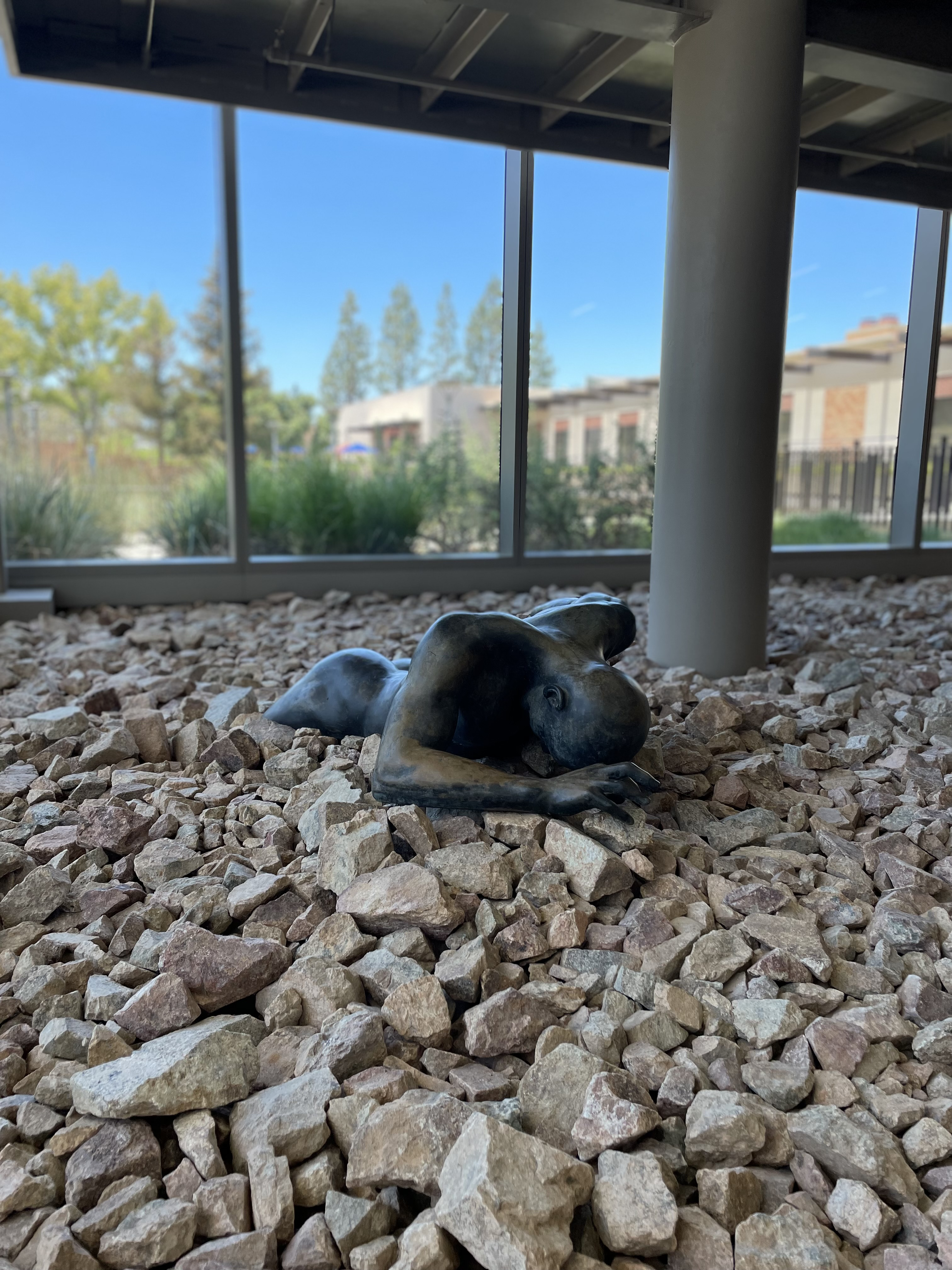 Figure crawling out of rocks in an interior space.
