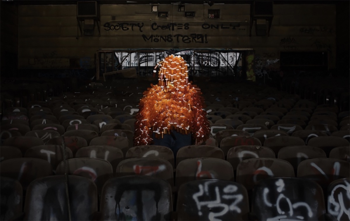 Dystopian theatre with graffitied walls and a mysterious figure.