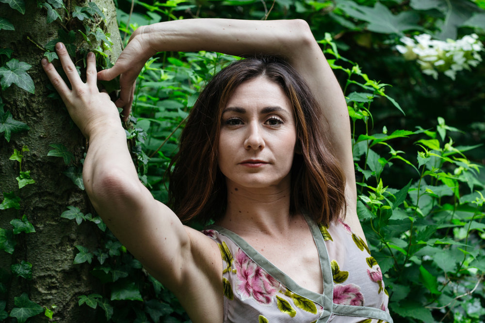 Woman standing near wall of foliage