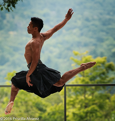 Dancer leaping into the air on an outdoor stage.