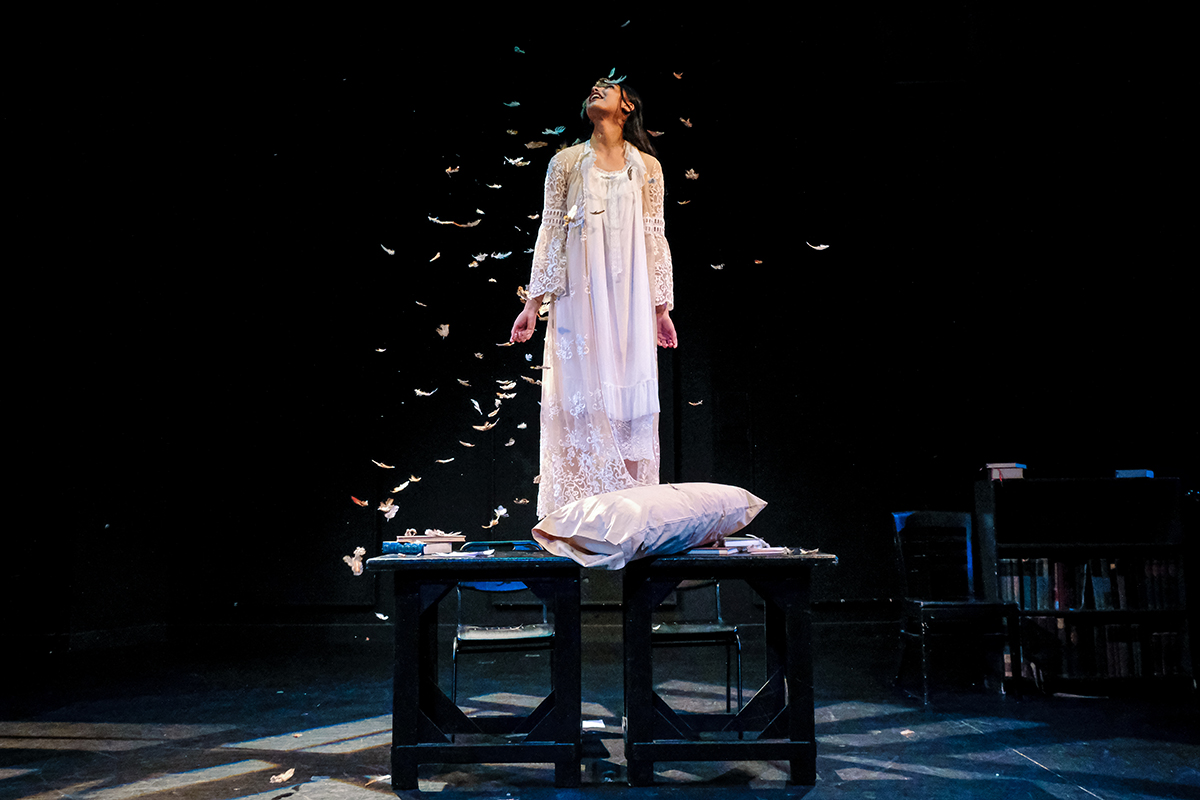 Actor looking skyward as feathers fall around them.