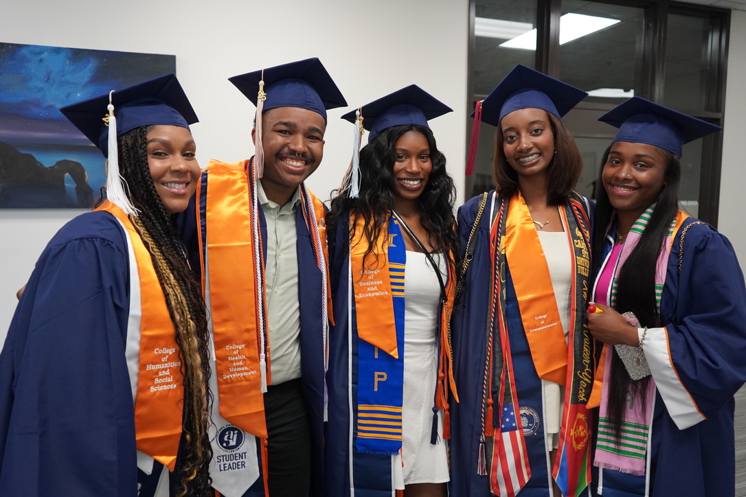 CSUF graduates in their robes smiling and embracing each other.  