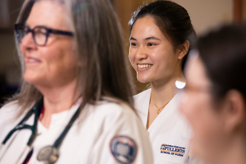 two women in a white lab coats smile 