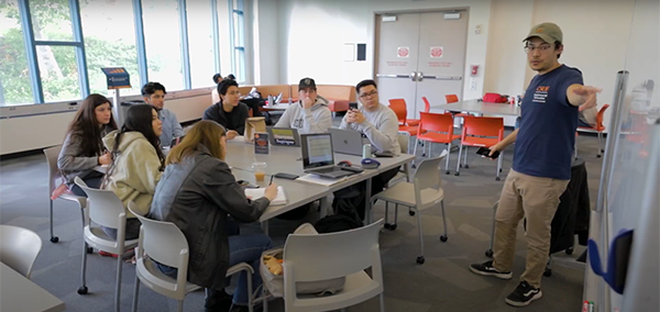 group seated at desks with si leaders instructing