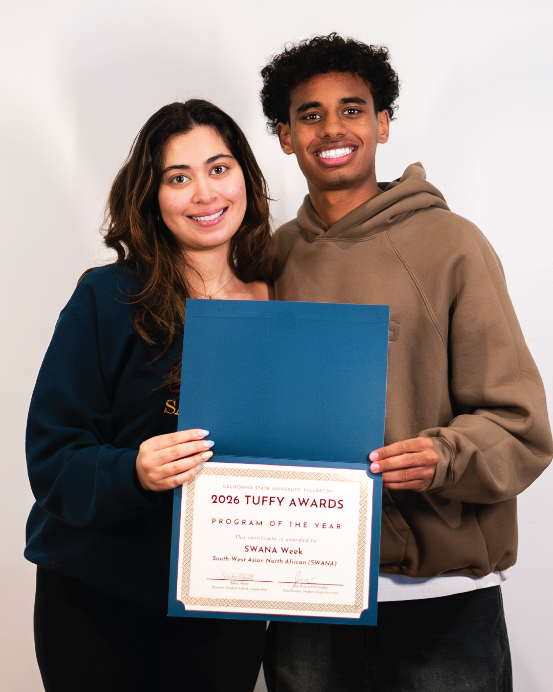 Two students holding an award for Program of the Year