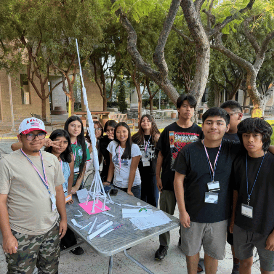 Students posing with a paper tower they constructed for a STEM activity.